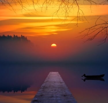 Coucher de soleil sur un lac avec une barque et une avancée en bois