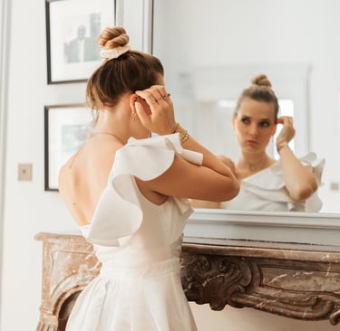 a woman in a white dress standing in front of a mirror