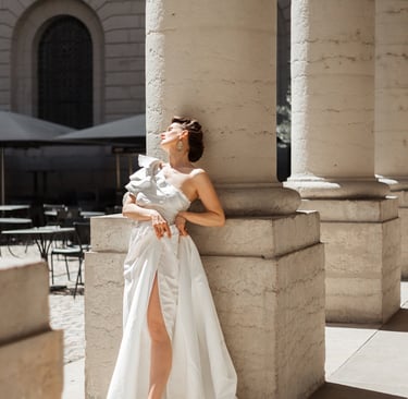 a woman in a white dress standing in front of a column