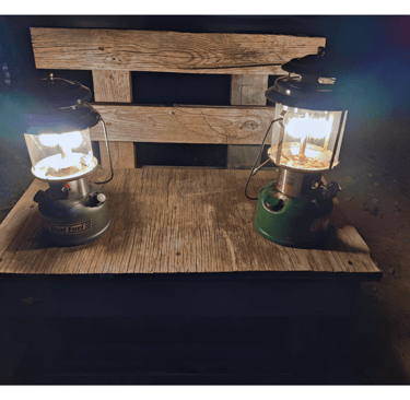 Two antique lanterns with thorium on top of a wooden bench.