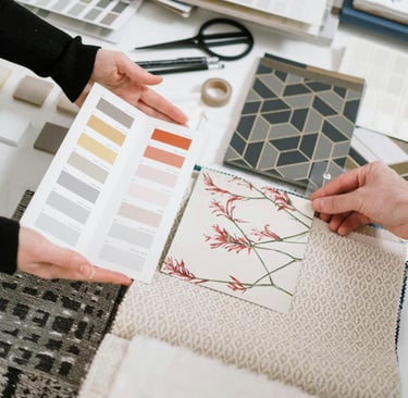 Designer de interiores apresentando amostras de decoração em uma mesa, destacando cores, texturas