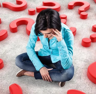 A thinking woman sitting on a floor with multiple red question marks around