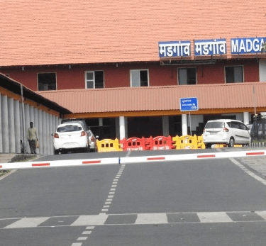 a gated entrance to a Margao railway station building with a sign board of Margao