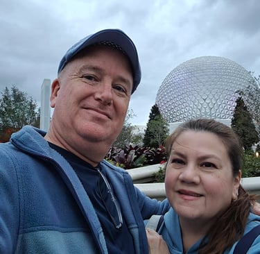 a man and woman taking a selfie in front of spaceship earth at Epcot
