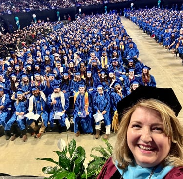 A graduation ceremony at a community college with students and president taking a selfie.