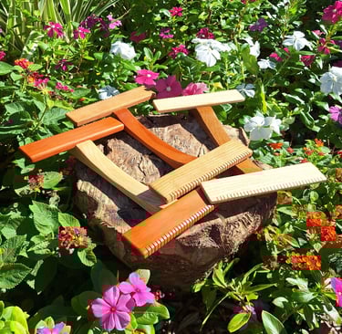 A collection of our hand looms. Three medium size hand looms of assorted woods in a flower garden.