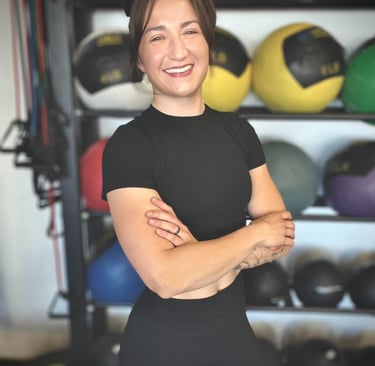 Female Personal Trainer standing in front of a medicine ball rack