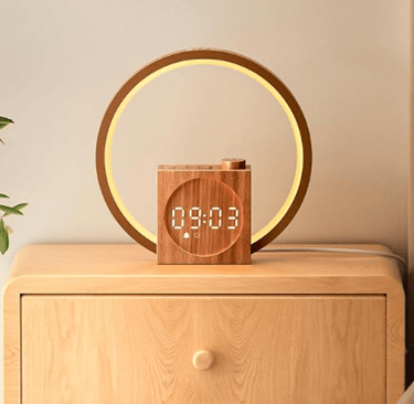 Dreamegg Sunrise alarm clock with wood-grain finish and warm glowing light on a bedside table.