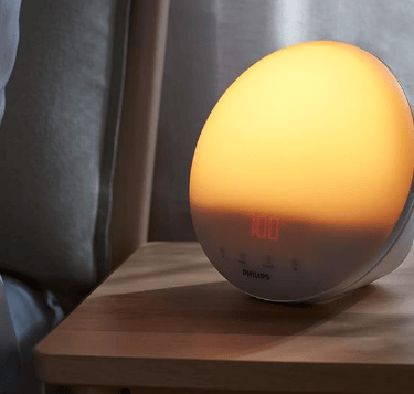Philips SmartSleep HF3520 wake-up light showing a vibrant orange and yellow sunrise simulation