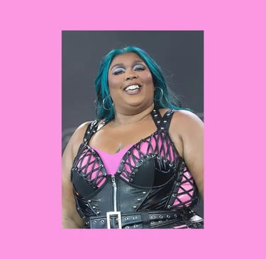 Lizzo singing on stage, wearing a black and pink outfit.