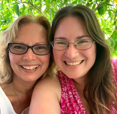Two women wearing glasses smile at the camera