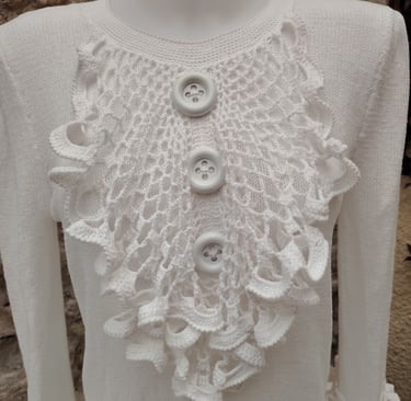 jabot sur un pull blanc deux gros boutons blanc son cousu dessus au milieu