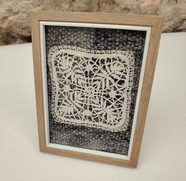 Ancien motif couleur crème fait au fuseau posé sur un fond tricoté en dégradé de gris