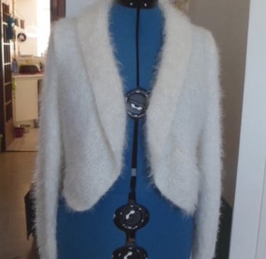 Modèle unique d'une veste tricoté à la main dans un fil couleur crème très doux
