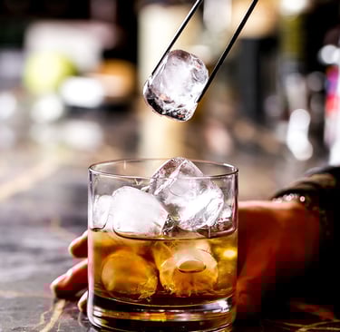 Μπάρμαν προσθέτει πάγο σε ποτήρι με ποτό