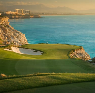 Luxury oceanside golf course green on a cliff overlooking the turquoise sea at sunset.