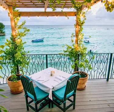 Luxury waterfront balcony dining with a view of boats on turquoise Caribbean waters.