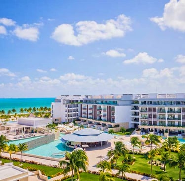 Luxury beachfront resort with turquoise ocean views, tropical palm trees, and swimming pools.