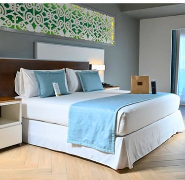 Modern luxury hotel room featuring a king bed with light blue accents and a decorative wall headboard.