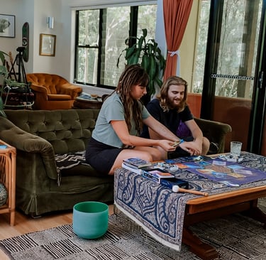 a woman and a man sitting on a couch doing a tarot oracle card reading