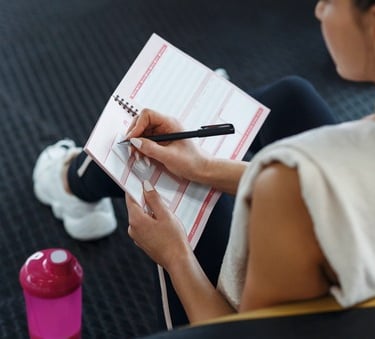 a young lady writing in a fitness planner