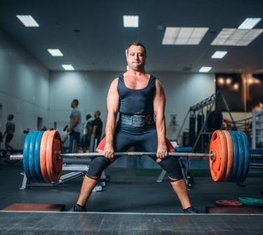 a man in a black top performing the deadlift
