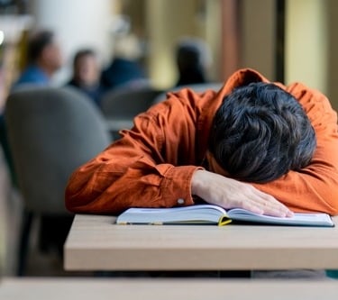 a man is sleeping on a desk in a library