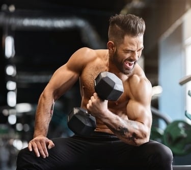 A muscular man performing a bicep curl with a heavy dumbbell in a gym for bodybuilding strength training.