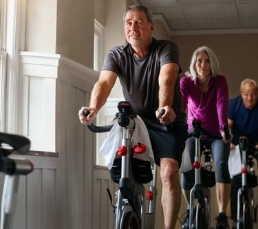 a man and woman riding bikes in a gym