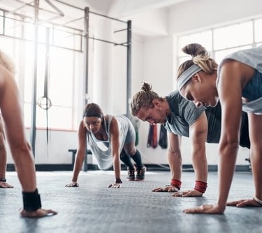 a group of people doing push ups in a gym