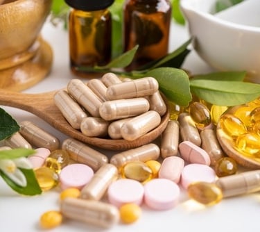 Natural herbal supplement capsules and vitamin softgels with essential oils and a mortar and pestle.