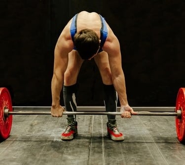Male athlete preparing for a deadlift with a heavy barbell and red weight plates.
