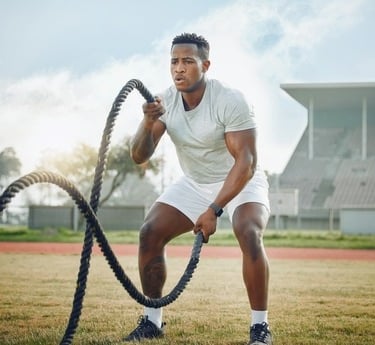 a man in white shirt and shorts using a battling rope