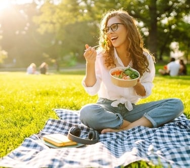 a woman sitting on a blanket in the grass