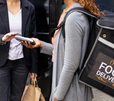 Customer using a credit card to pay a food delivery courier on a mobile POS terminal.