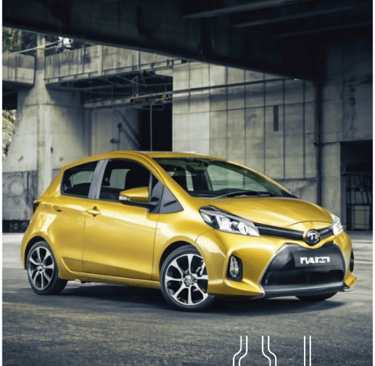 a yellow toyota yaris hatchback parked in front of a building