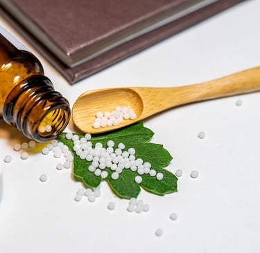 a bottle of homeopathic medicated pills and a wooden spoon on green leaf to take medicated pills 