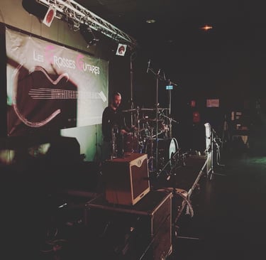 a man standing in front of a stage with a microphone and a guitar