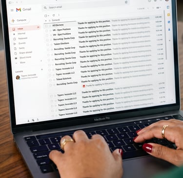 A black woman on a laptop scrolling her Gmail inbox filled with jobs she applied to emails.