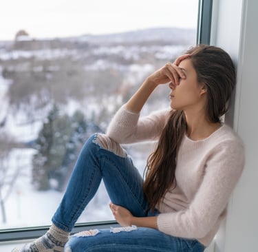 mulher sentada, com a mão no rosto, demonstrando tristeza