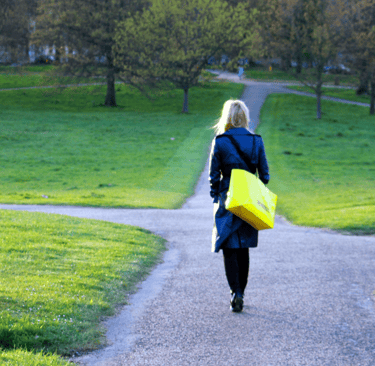 uma mulher caminhando por uma pequena estrada, meio quem sem rumo