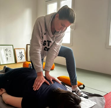 Professional practitioner performing a traditional Shiatsu massage therapy session on a floor mat.
