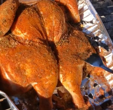 Spatchcocked whole chicken coated in homemade Cajun seasoning on charcoal grill