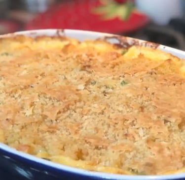 Cheesy classic tuna casserole baked in a dark blue ceramic casserole dish on top of a gas stove
