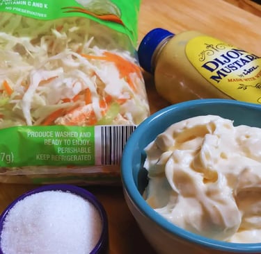Coleslaw ingredients arranged on a wooden cutting board, including cabbage, carrots, and seasoning items