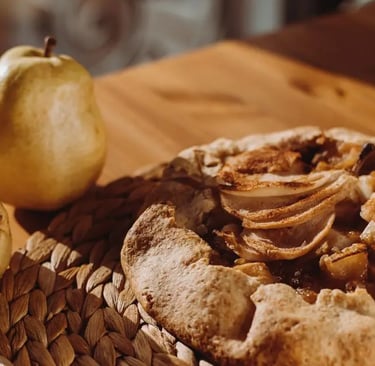 pear galette on a wooden table beside two fresh pears
