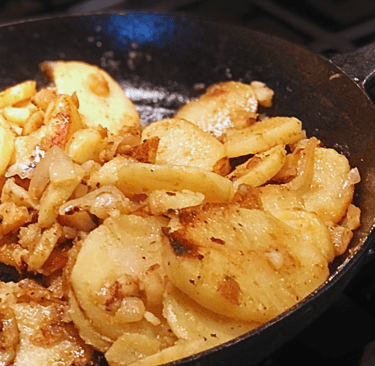 fried skillet postatoes on a stove in  cast iron skillet pan
