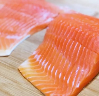 two uncooked steelhead trout fillets on cutting board