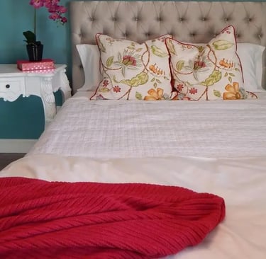 bedroom with teal walls with fall decor accents of a burgundy throw and two fall decorated pills