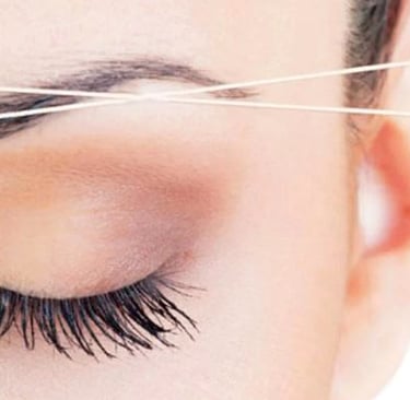 una mujer depilandose las cejas con hilo natural 